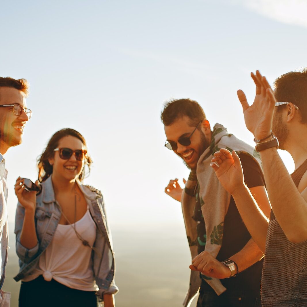 three men and one woman laughing during daytime