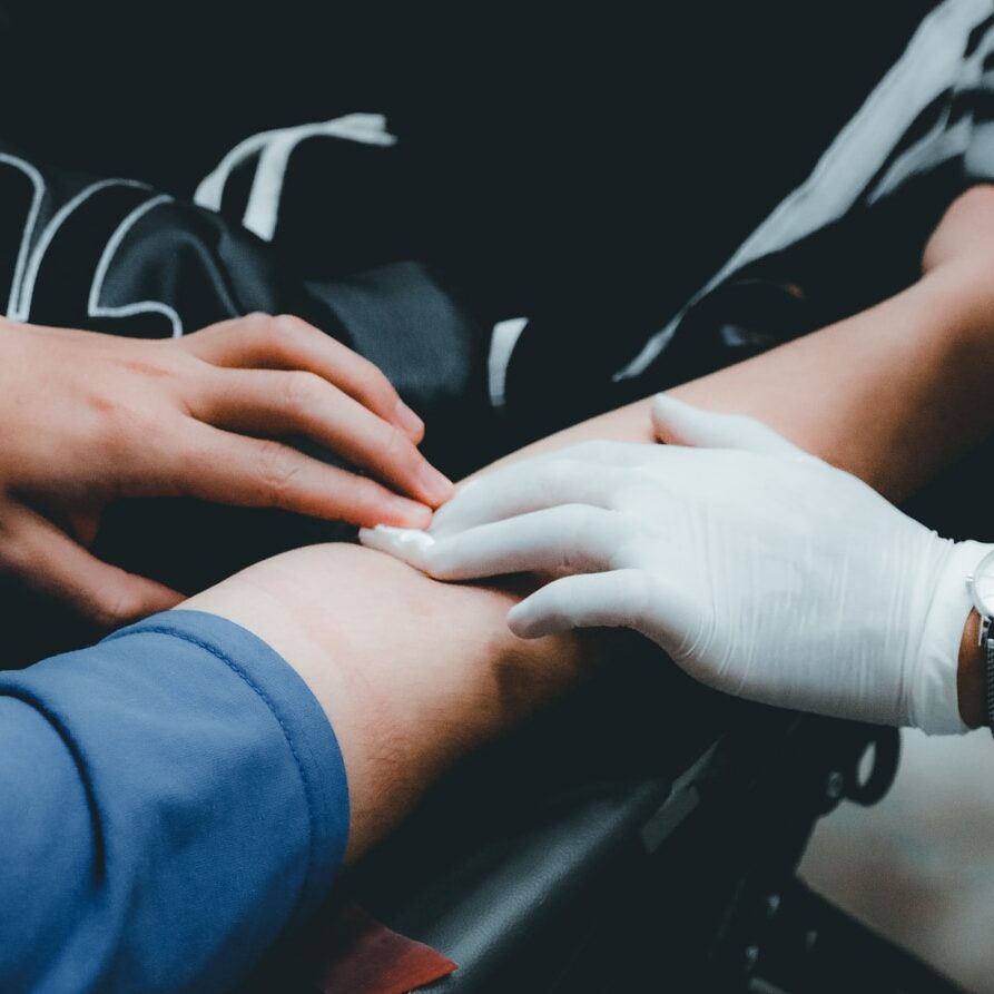 blood drive person in blue long sleeve shirt holding persons hand